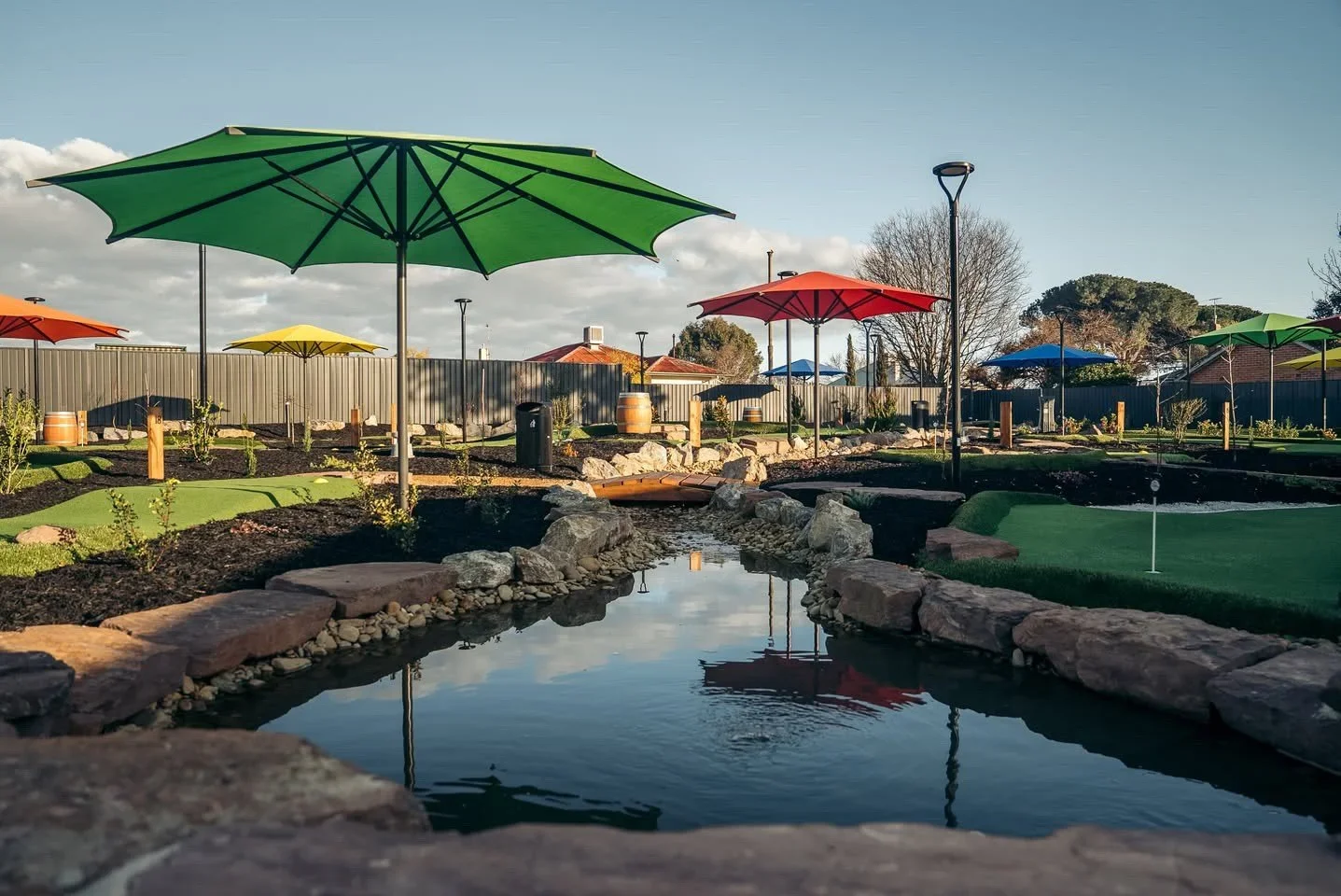 A mini gold course with umbrellas and ponds