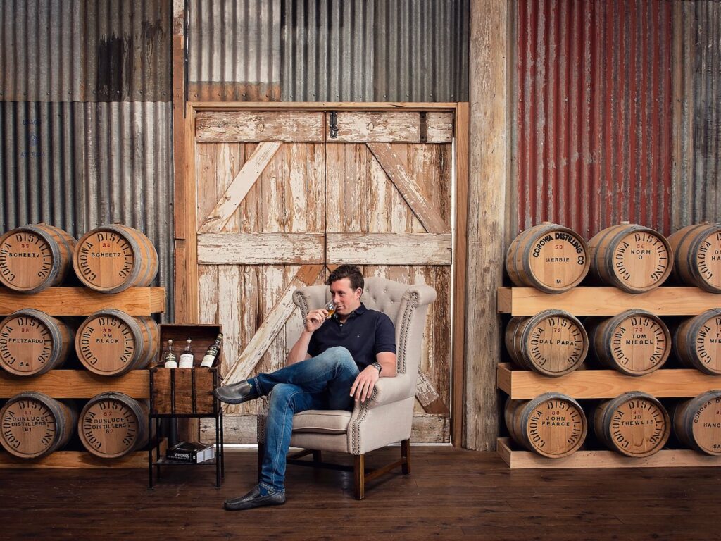 A man in a chair with a whisky in his hand